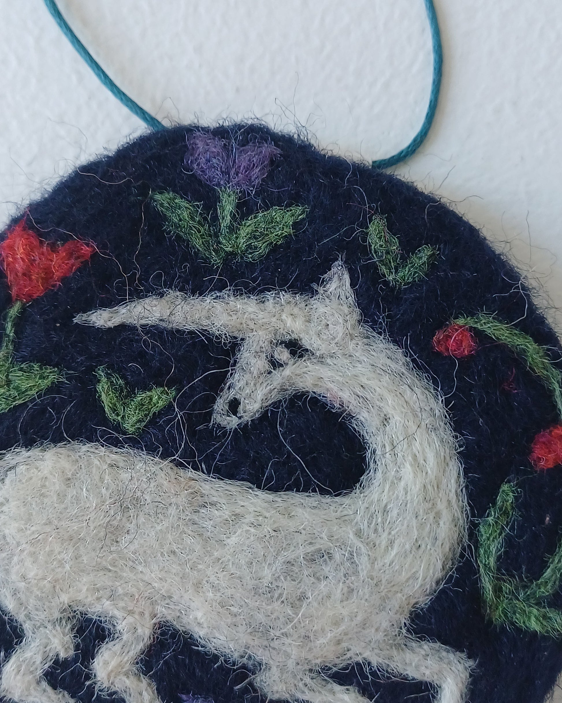 needle felted decoration with a white unicorn design on a dark blue background
