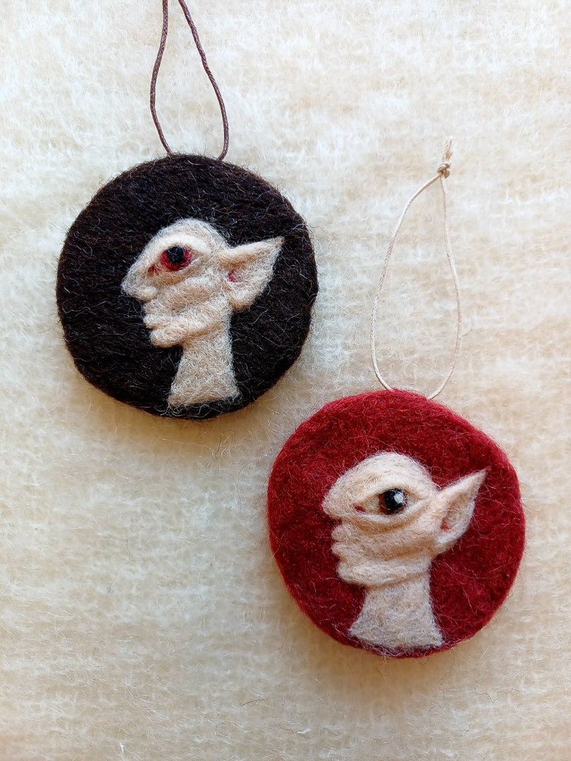 Two needle felted hanging ornaments featuring pale goblins in side profile, each with pointed ears and huge eyes.