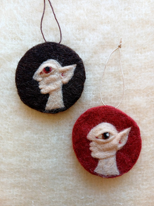 Two needle felted hanging ornaments featuring pale goblins in side profile, each with pointed ears and huge eyes.
